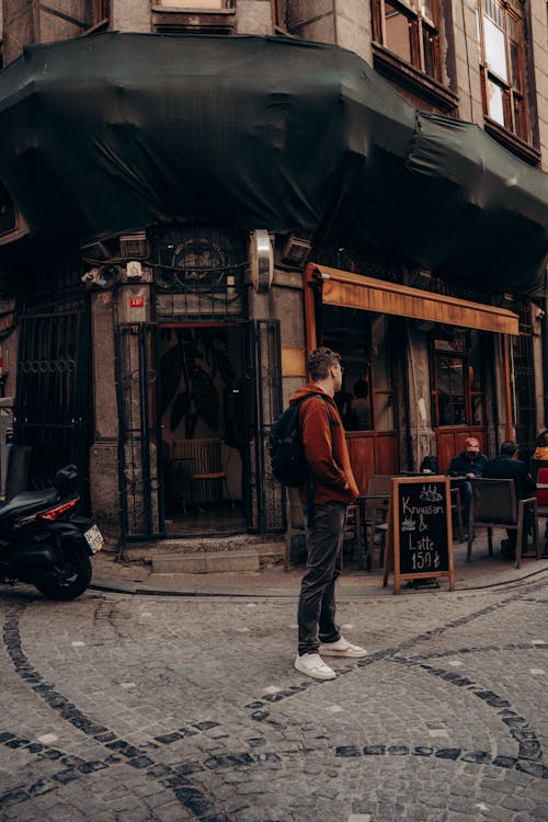 A man standing on the street in front of a cafe