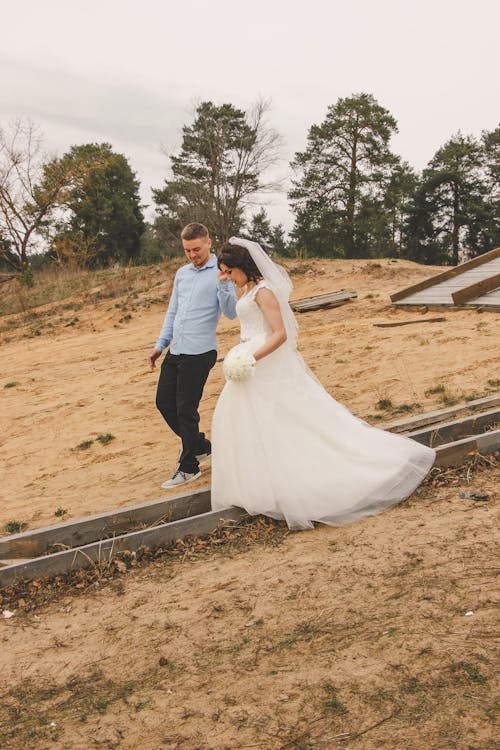 A bride and groom walking on a dirt path