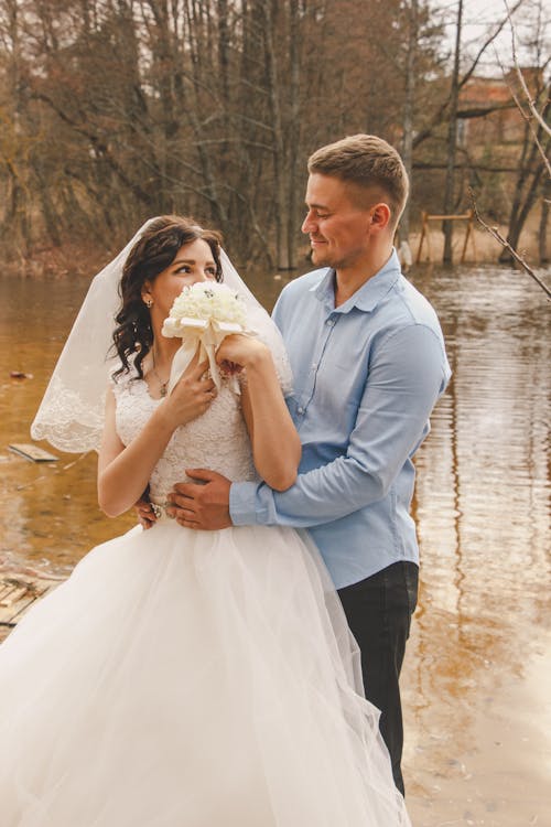A bride and groom standing in the water near a river