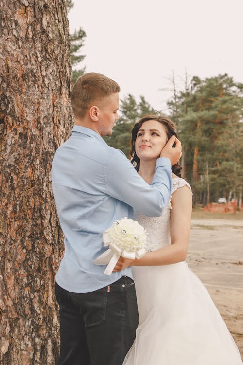 A bride and groom hugging by a tree