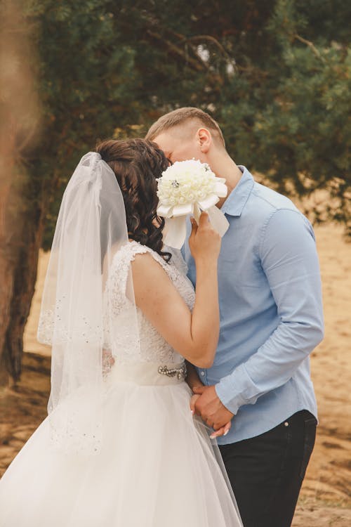 A bride and groom kiss in front of a tree