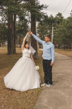 Bride and groom share a romantic dance in a tranquil park setting.