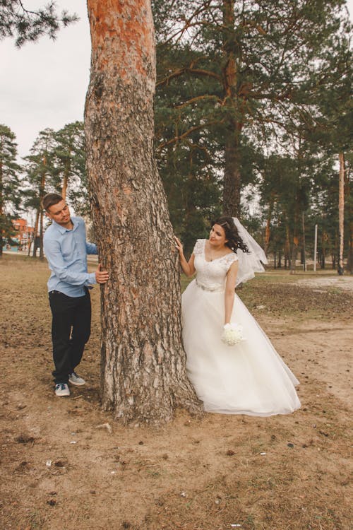 A bride and groom standing next to a tree