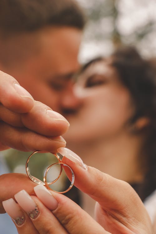 A man and woman holding wedding rings