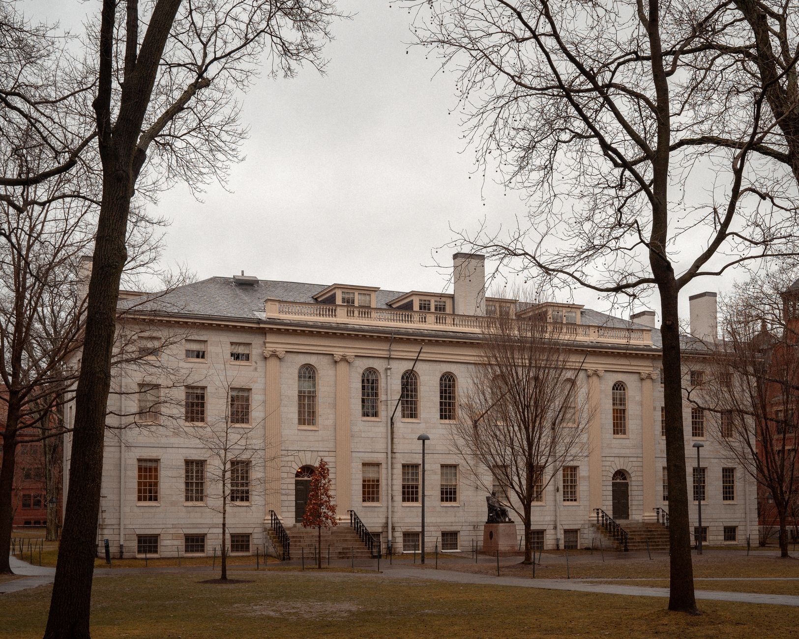 A historic university building surrounded by barren trees on an overcast autumn day.
