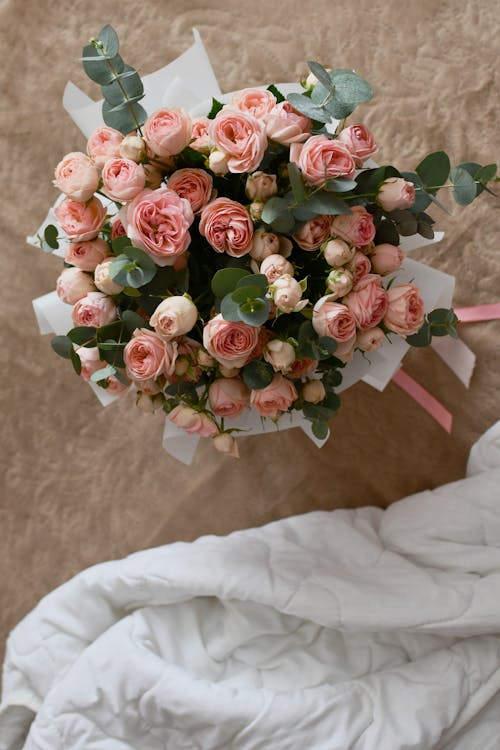 A bouquet of pink roses is sitting on a bed