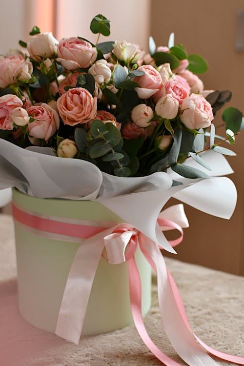 A bouquet of pink roses in a green box