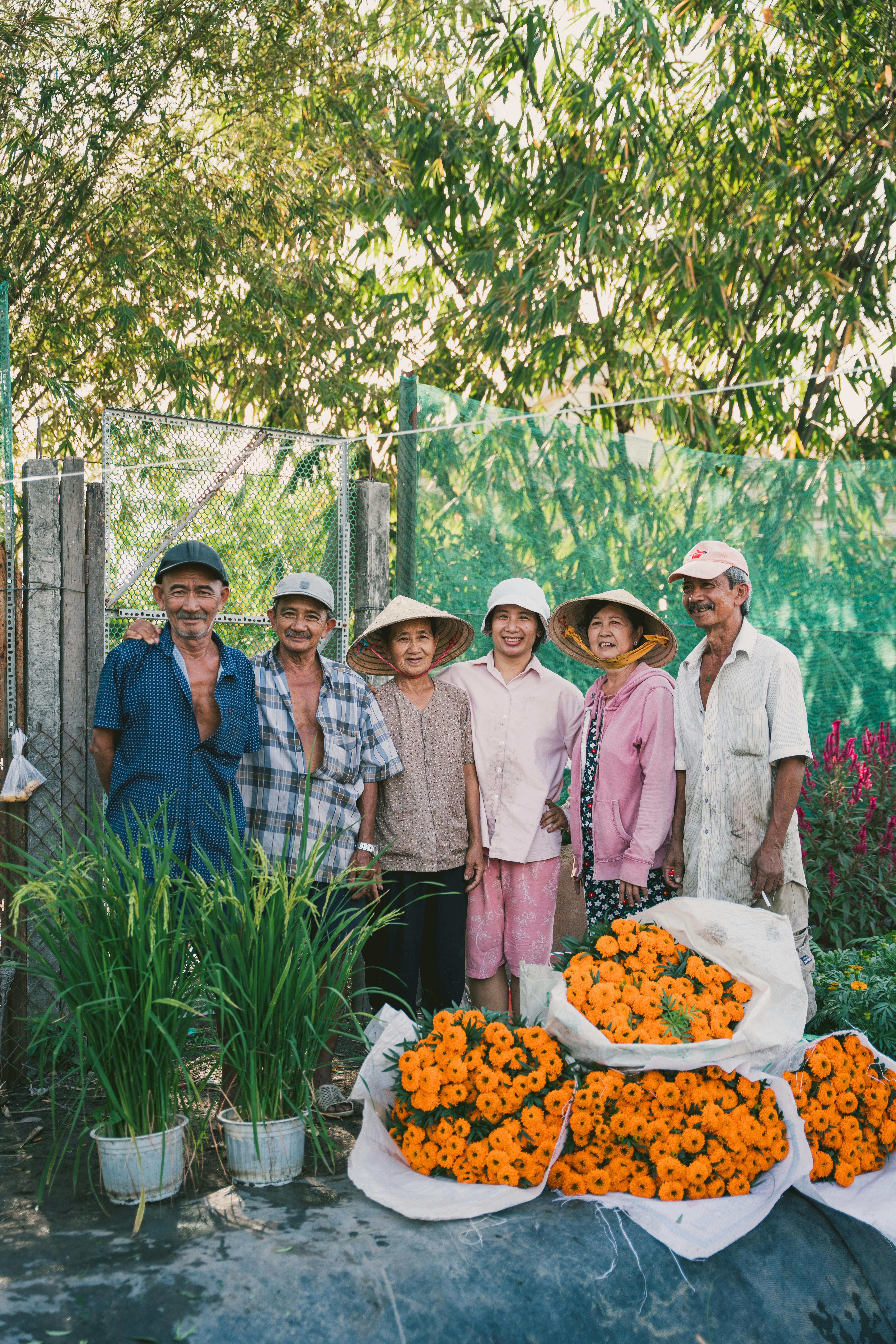 Happy Vietnamese farmers posing with a vibrant flower harvest in Ho Chi Minh City garden.