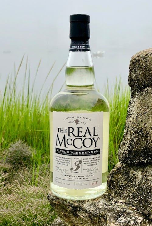 A bottle of real mccoy whisky sitting on a rock