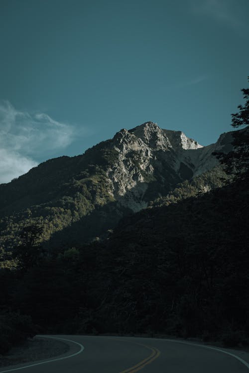 A mountain road with a blue sky and a green mountain