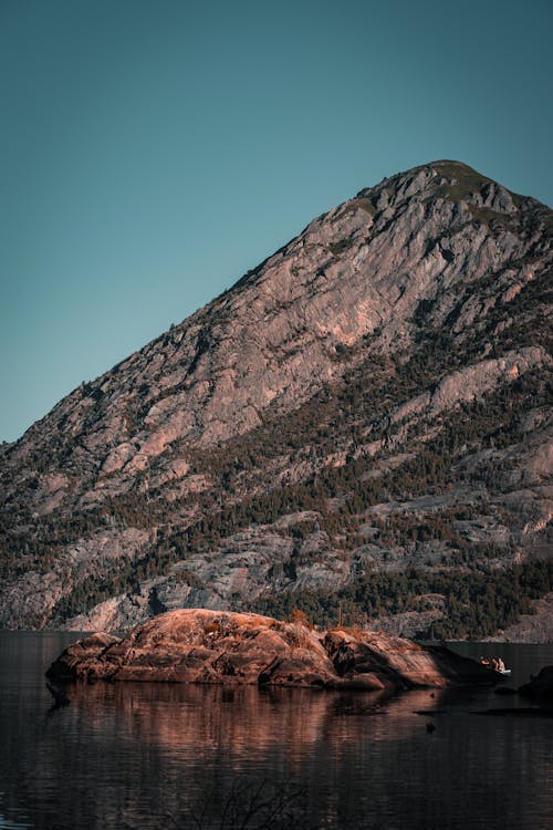 A mountain with a rock in the water