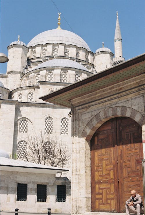 A man sitting on a bench in front of a mosque