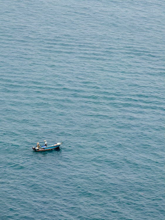 Free A small boat in the ocean with two people in it Stock Photo