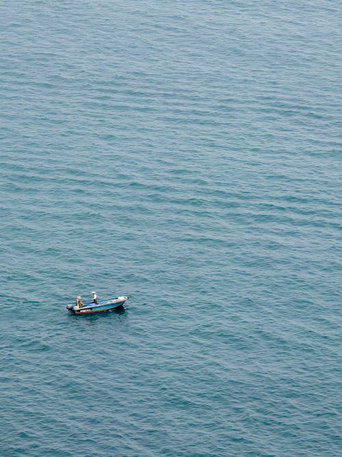 Free A small boat in the ocean with two people in it Stock Photo