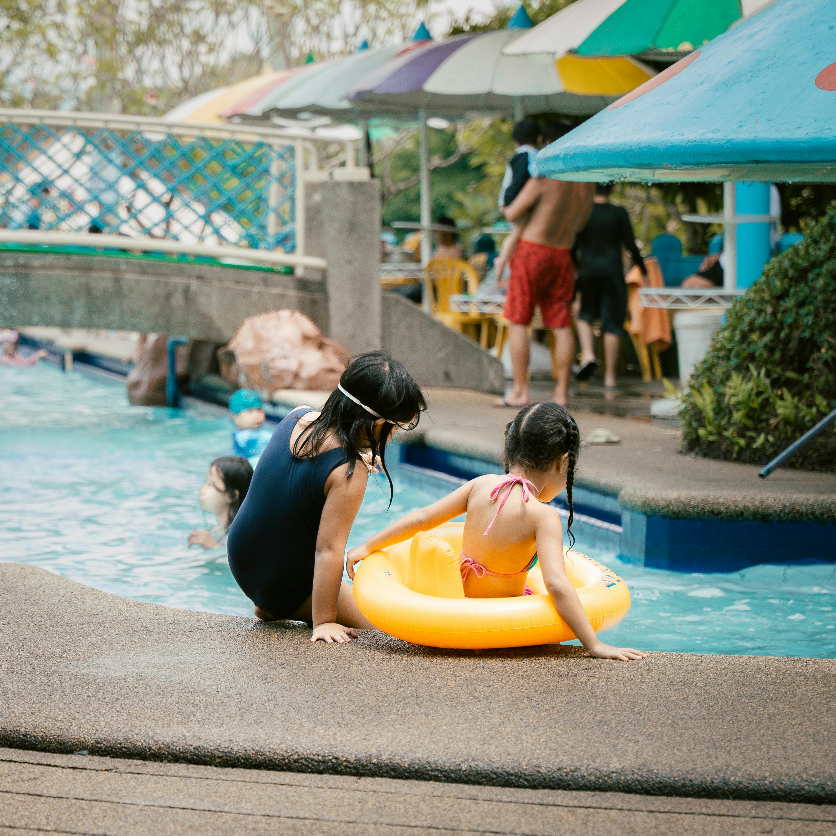 Two girls having fun by the swimming pool at a resort, enjoying their vacation.