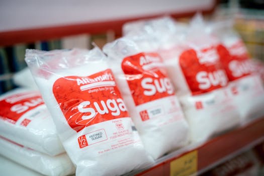 Close-up of sugar bags on a grocery store shelf, highlighting product packaging.
