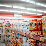 Wide shot of vibrant snack aisle in a supermarket with various chip bags on display.