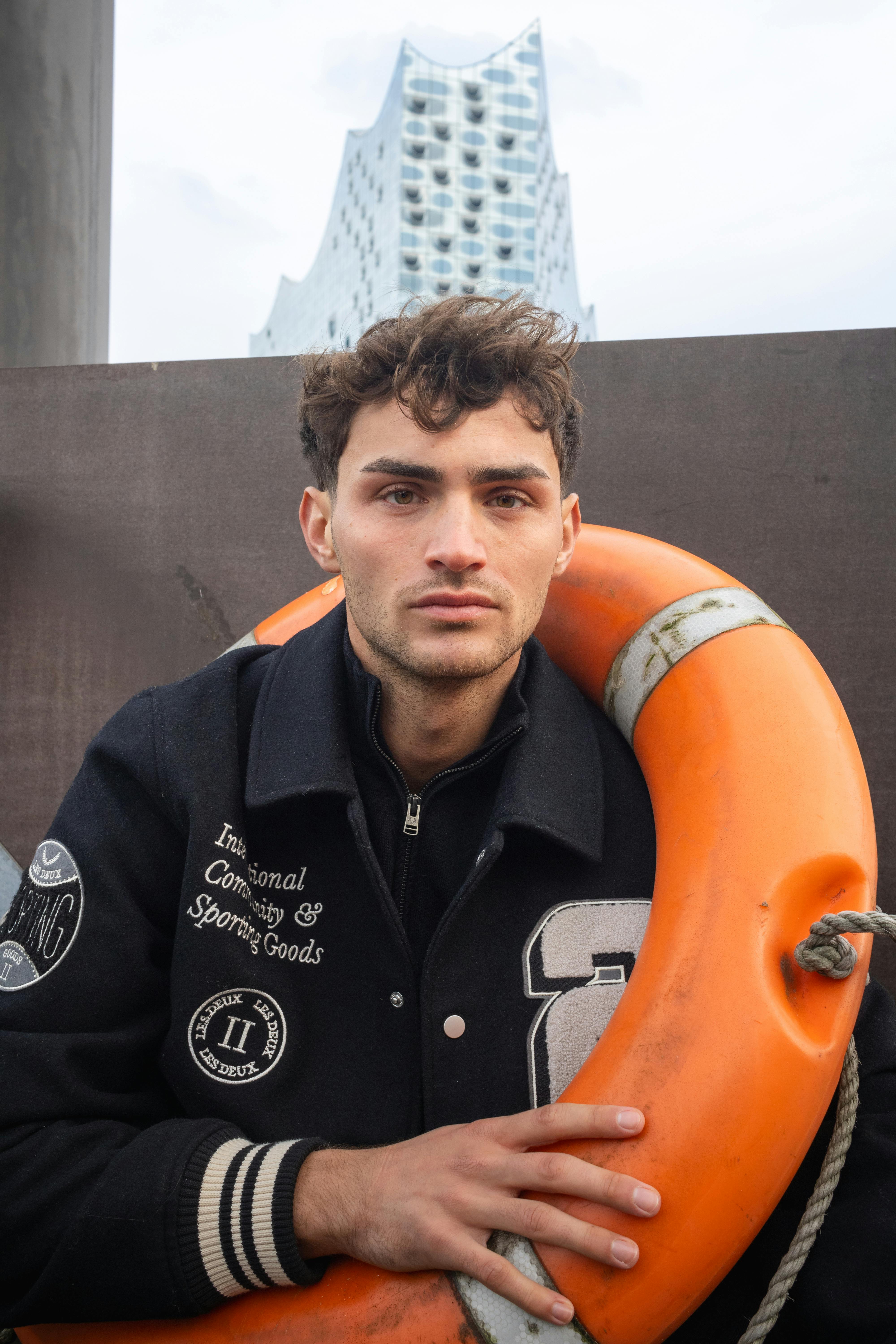 Portrait of a man in Hamburg with a life belt and iconic architecture in the background.