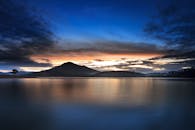 暮光映照在宁静的湖面上，五彩缤纷的天空映衬着群山