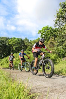 Three cyclists enjoy mountain biking through lush greenery in Batangas, Philippines.