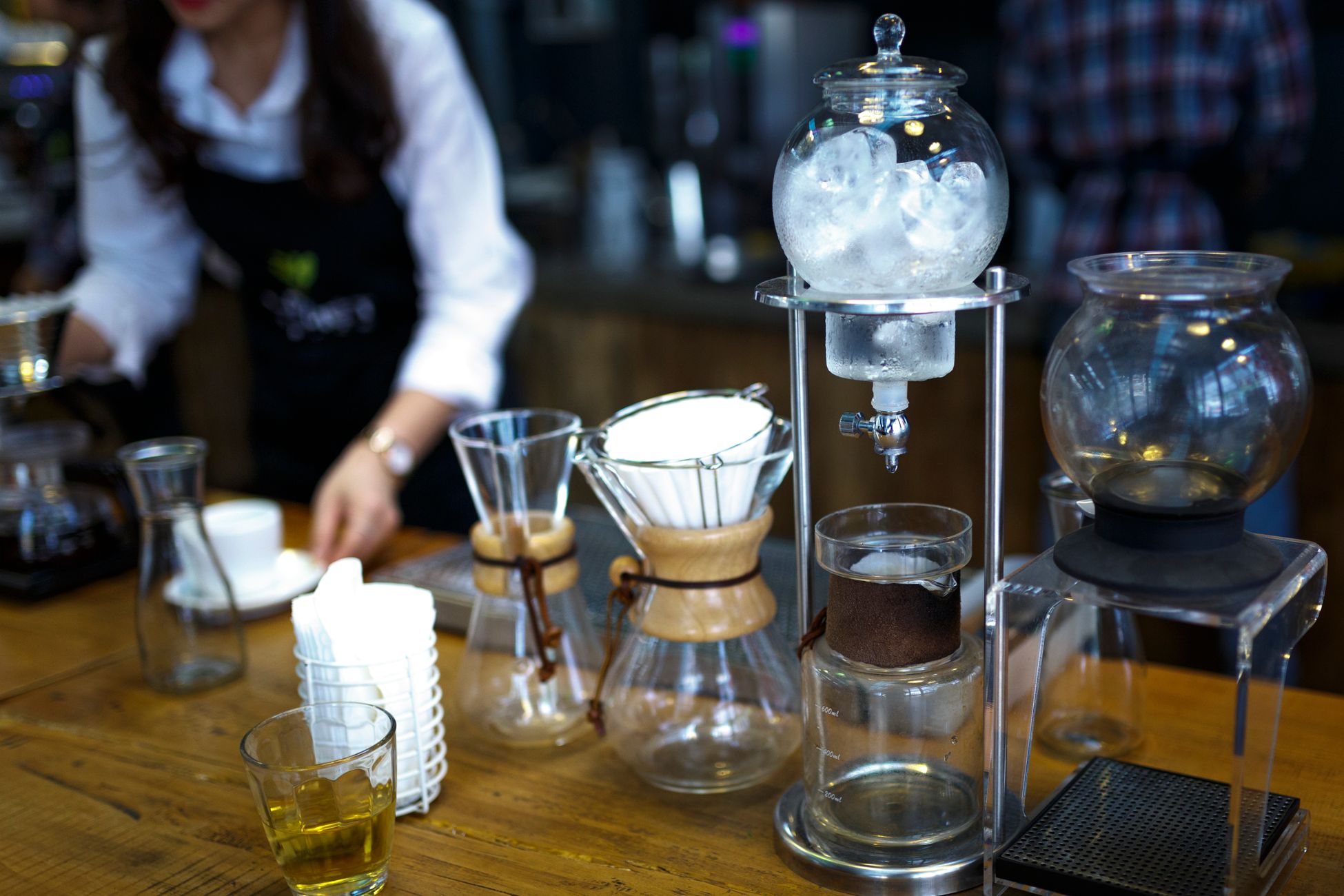 Artistic setup of drip coffee equipment in a cafe with glass containers and ice.