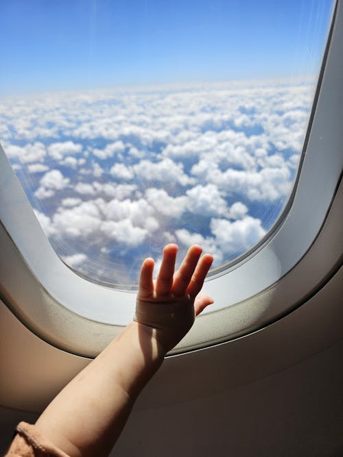 A child's hand reaching out of an airplane window