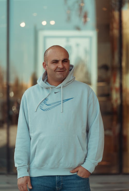 A man in a blue hoodie standing in front of a store