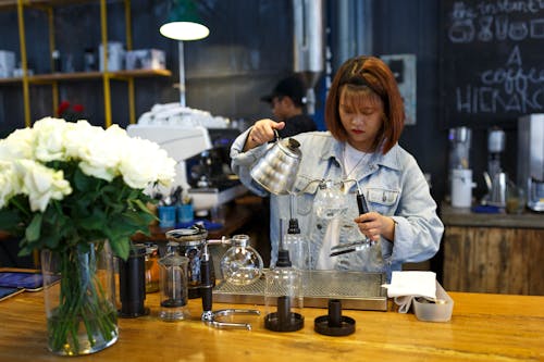 Free Woman Holding Kettle While Standing at the Table Stock Photo