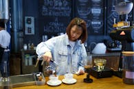 在一家别致现代的咖啡店里，一位专注的咖啡师正小心翼翼地将咖啡倒入杯中