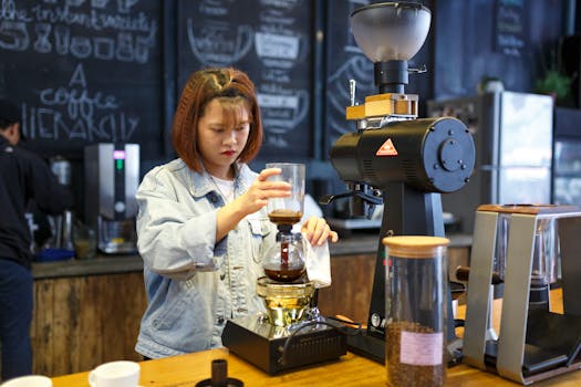 Barista using syphon method to prepare coffee in a café setting. Indoors with coffee equipment.