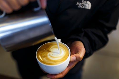 Free Person Pouring Cream to Coffee Stock Photo