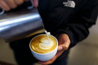 咖啡师在咖啡店将牛奶倒入卡布奇诺杯，创作拿铁艺术的特写镜头