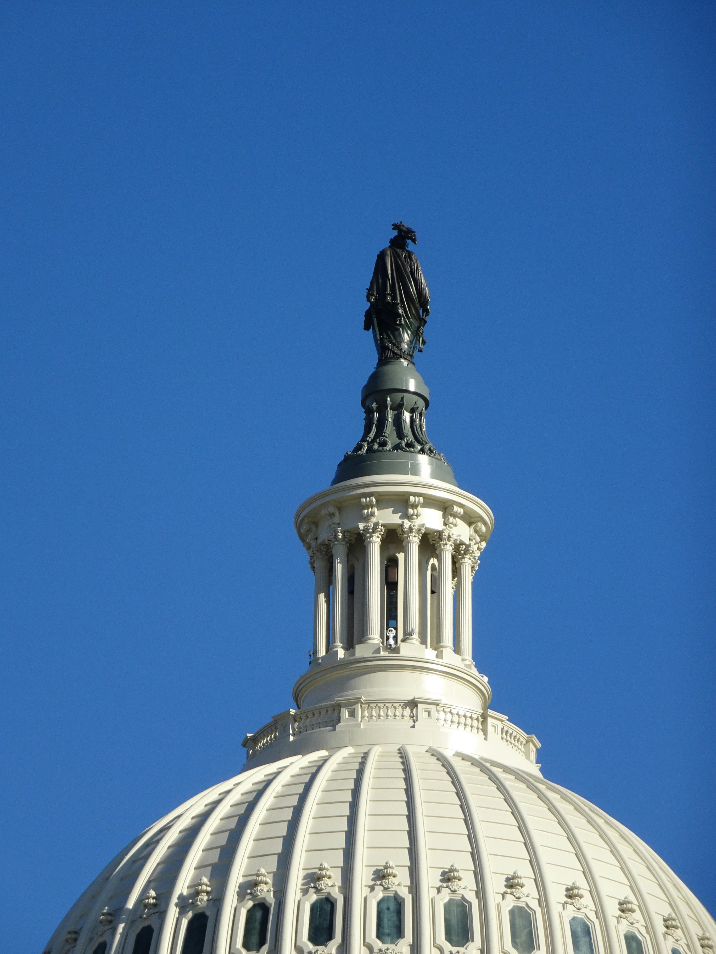 Close-up of U.S. Capitol dome with Statue of Freedom, Washington D.C., clear sky.