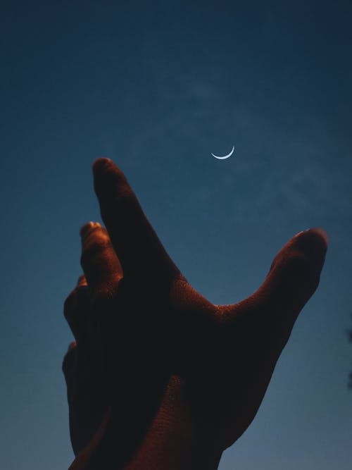 Free A person's hand reaching up to the moon Stock Photo
