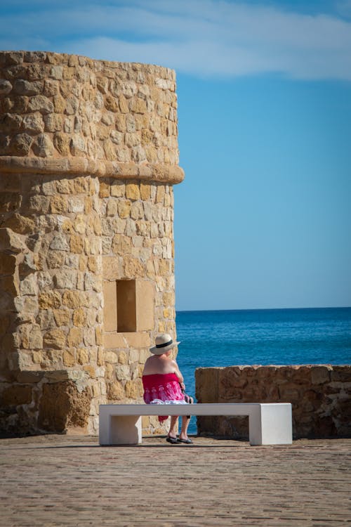 A woman sitting on a bench near a stone wall