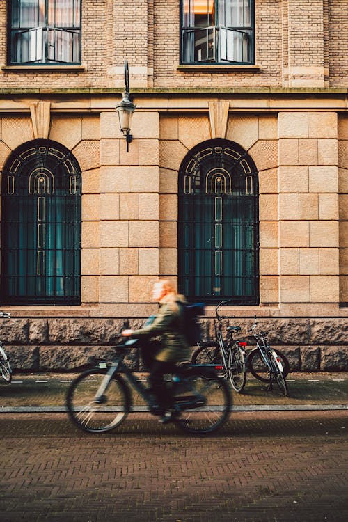 A person riding a bike down a street in front of a building