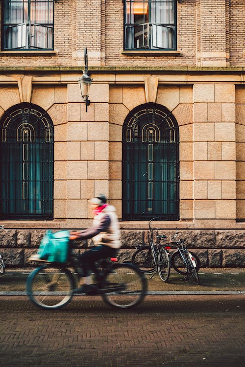 Free A person riding a bike down a street in front of a building Stock Photo