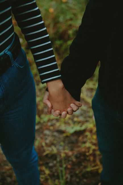 Fotomural Una pareja de manos unidas al aire libre, simbolizando amor y conexión, con un fondo natural difuminado.