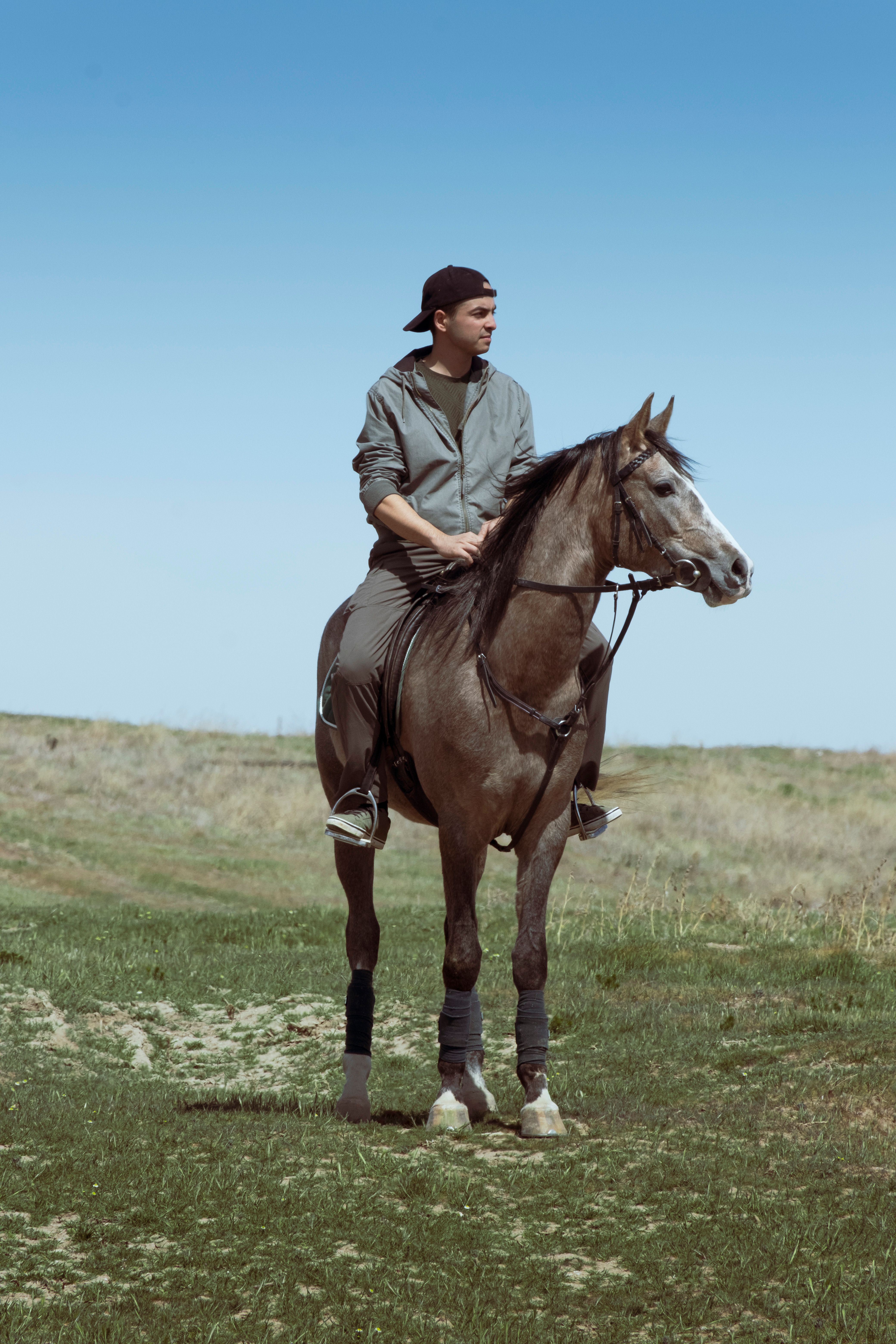 A young man riding a horse in a grassy field under a clear blue sky in Konya, Türkiye.