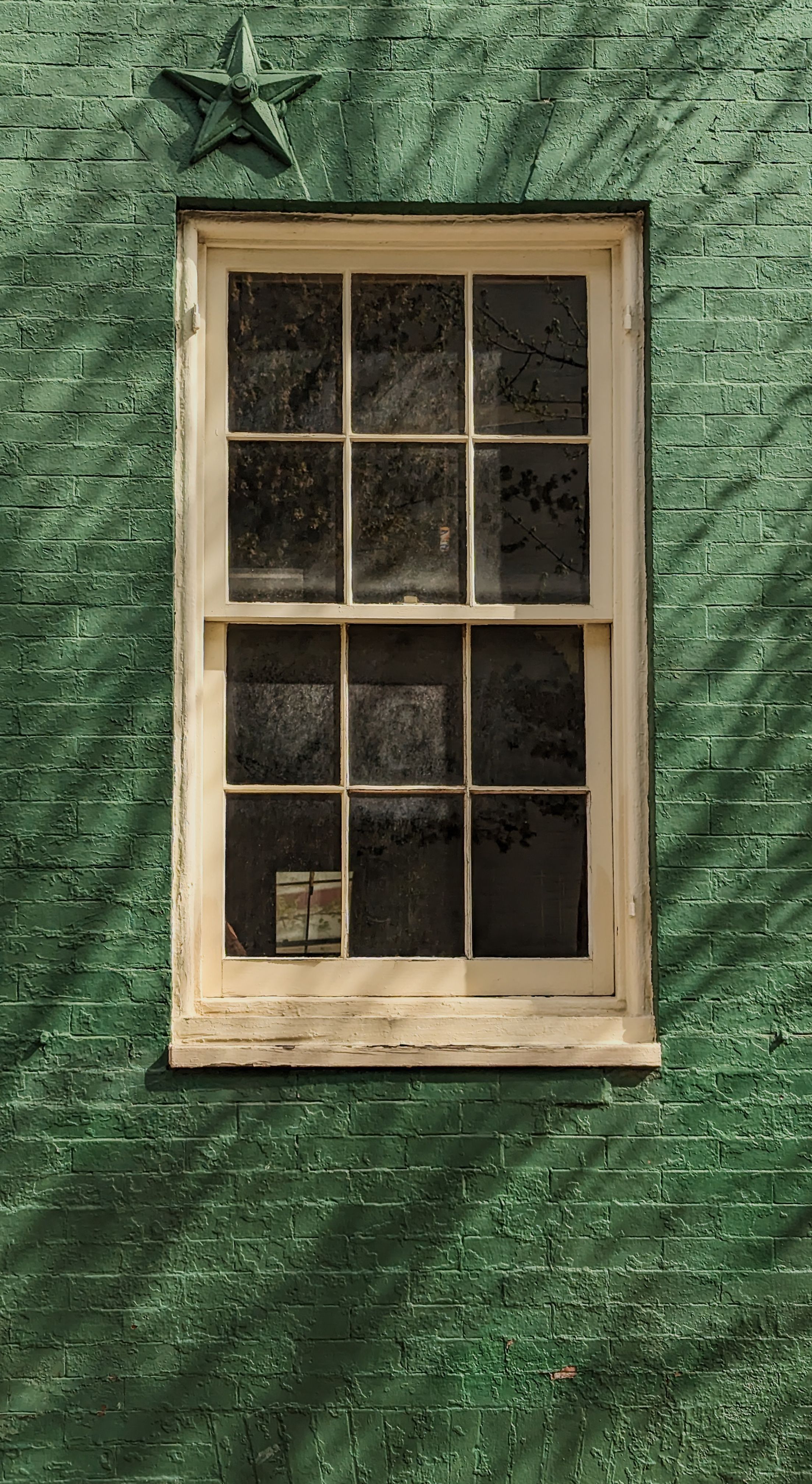 A historic window set in a vibrant green brick wall in Baltimore, MD