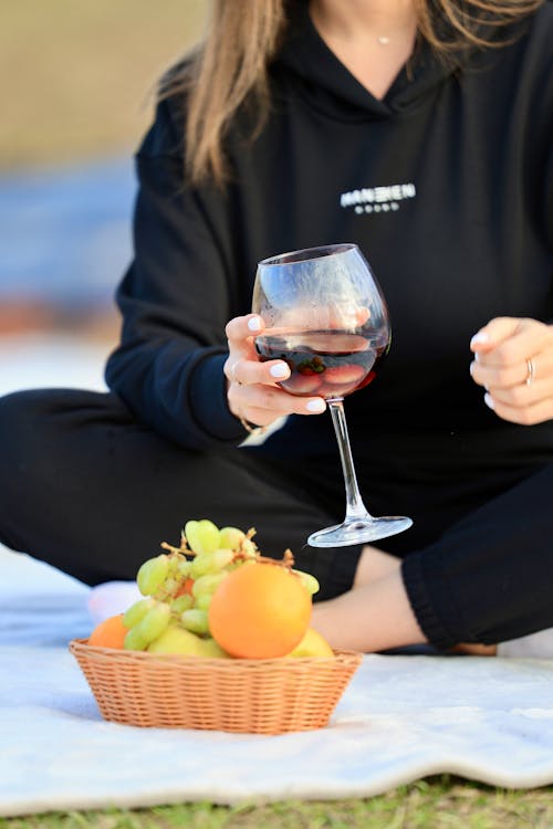 A woman in a black hoodie holding a glass of wine