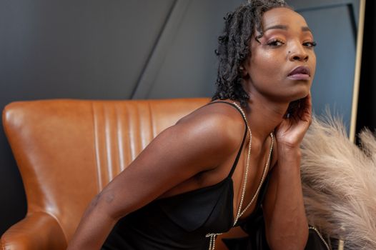Portrait of a Female Model Wearing a Black Dress Sitting in an Armchair