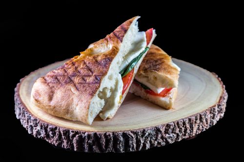 Free Appetizing grilled sandwich with cheese and tomatoes on a rustic wooden board. Perfect for lunch or a picnic. Stock Photo