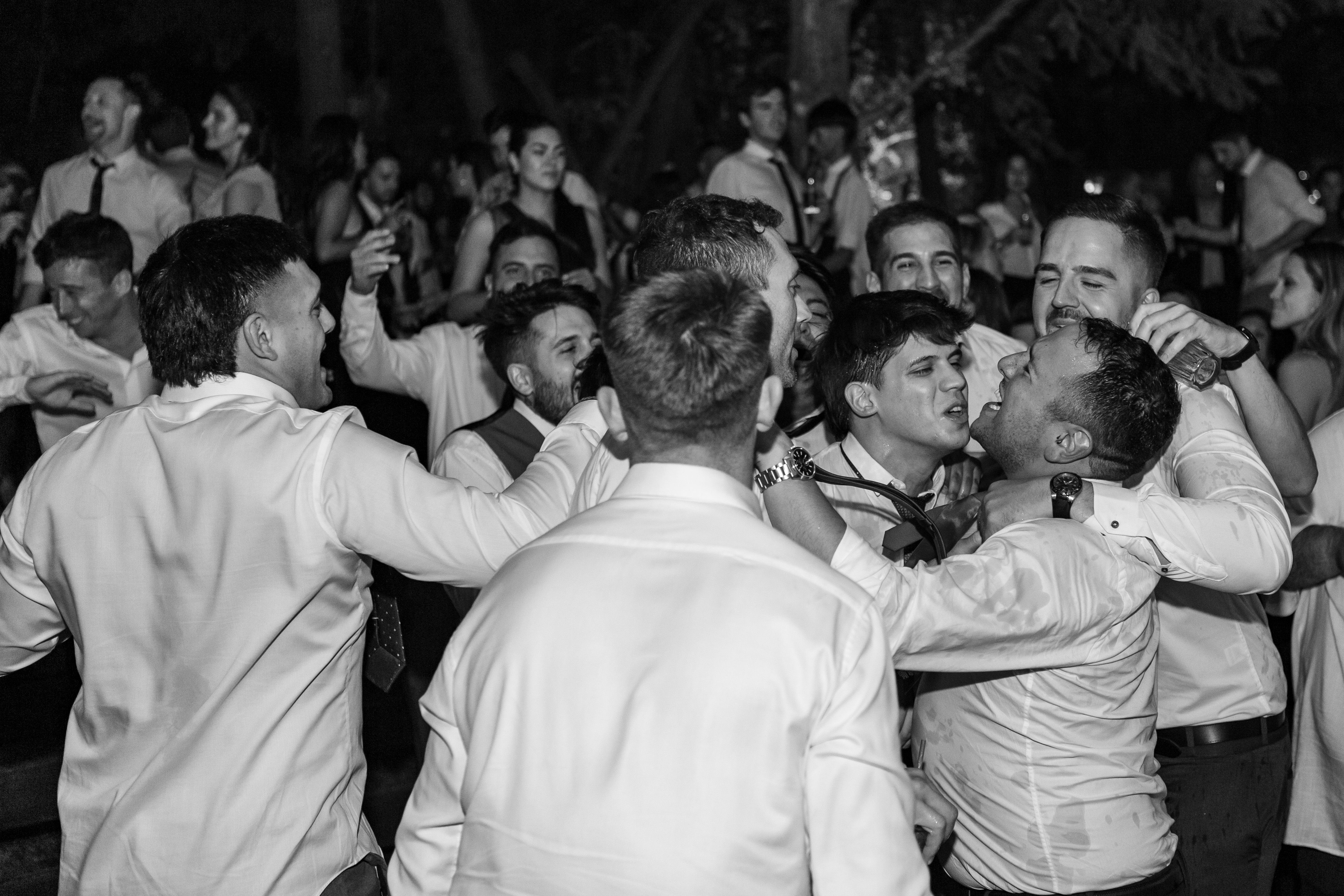 Group of men in formal attire celebrating and dancing at a party in Mendoza, Argentina.