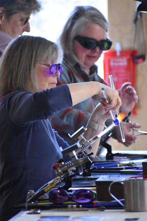 Two women are working on glass blowing