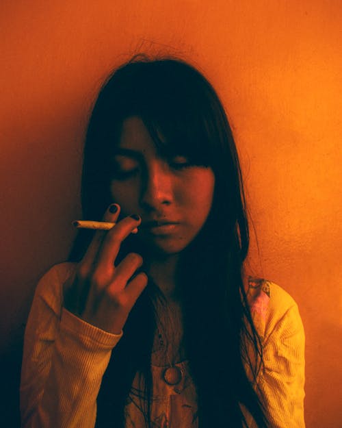 Gratis lagerfoto af asiatisk kvinde, cigaret, gul baggrund