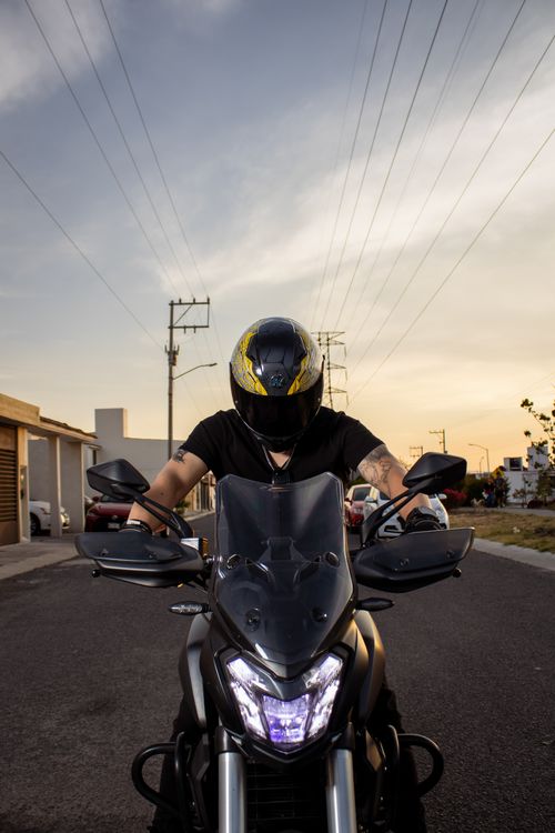 Free A motorcyclist with a helmet rides through a street at sunset in Santiago de Querétaro, Mexico. Stock Photo