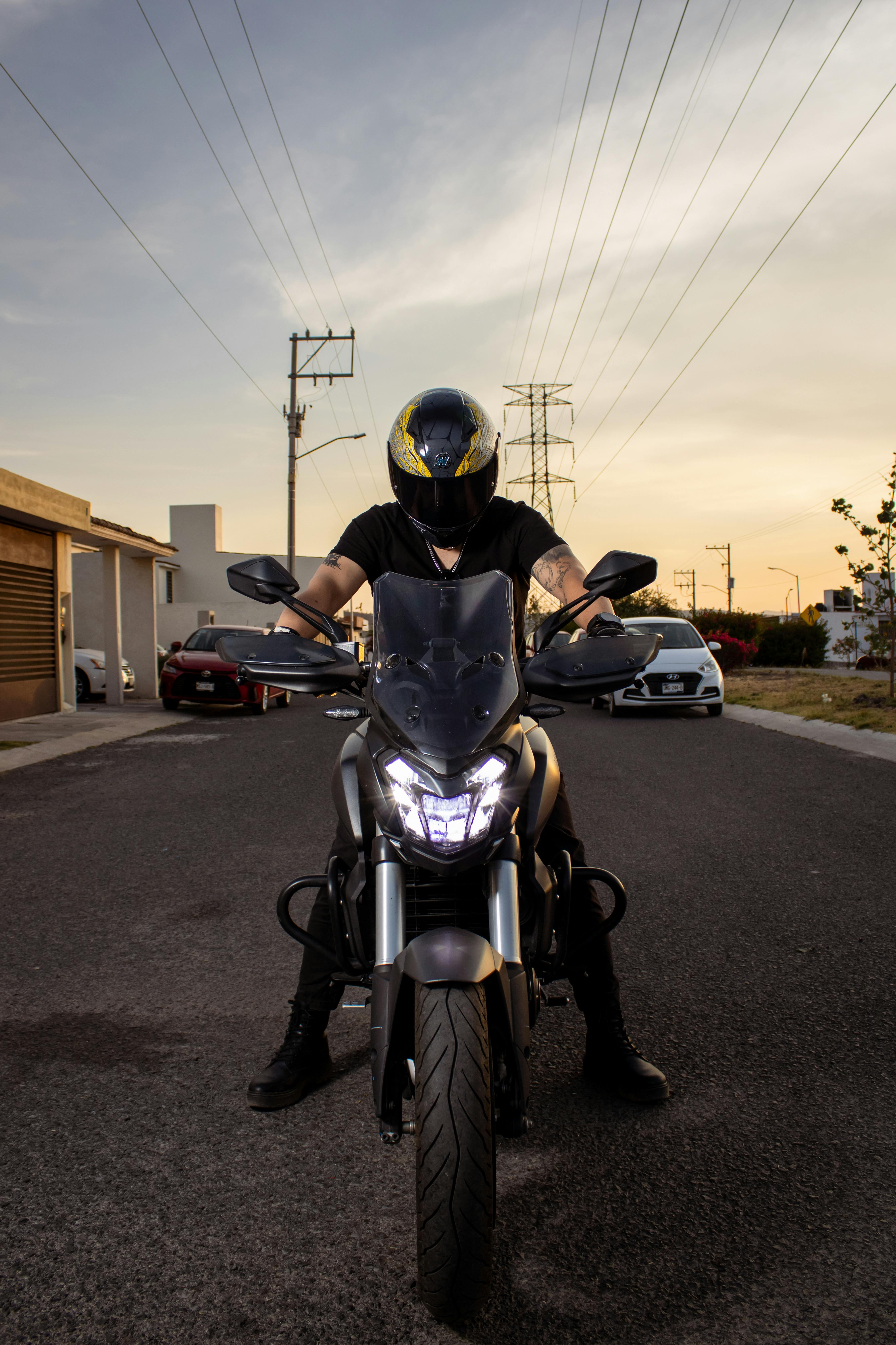 Free A motorcyclist wearing a helmet rides on a city street in Santiago de Querétaro at sunset. Stock Photo