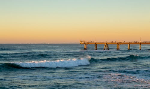 A pier with waves crashing on it at sunset