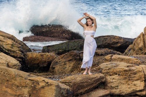 Free A woman in a white dress standing on rocks Stock Photo